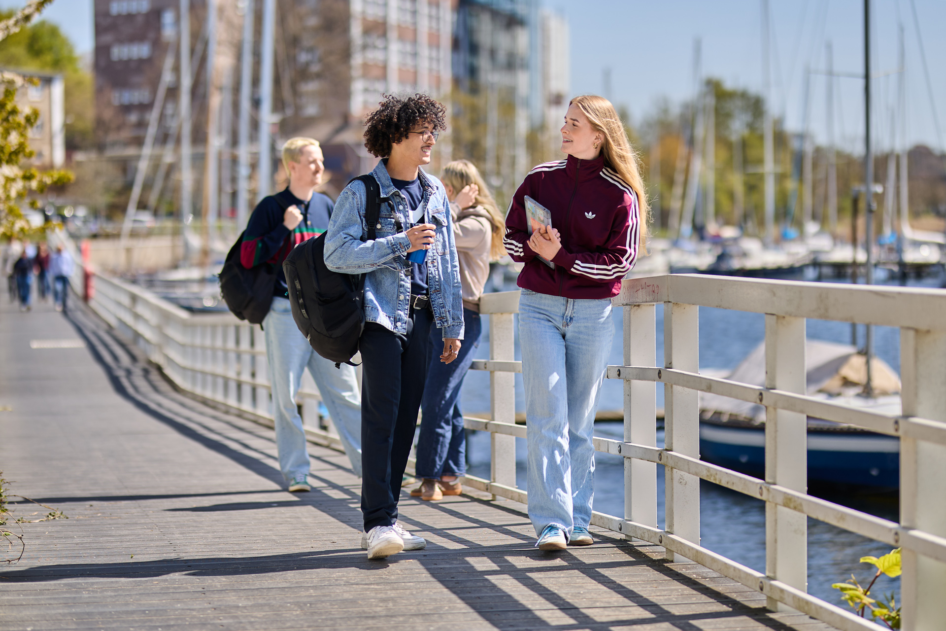 Studierende der HAW Kiel gehen auf einem Steg am Wasser und unterhalten sich