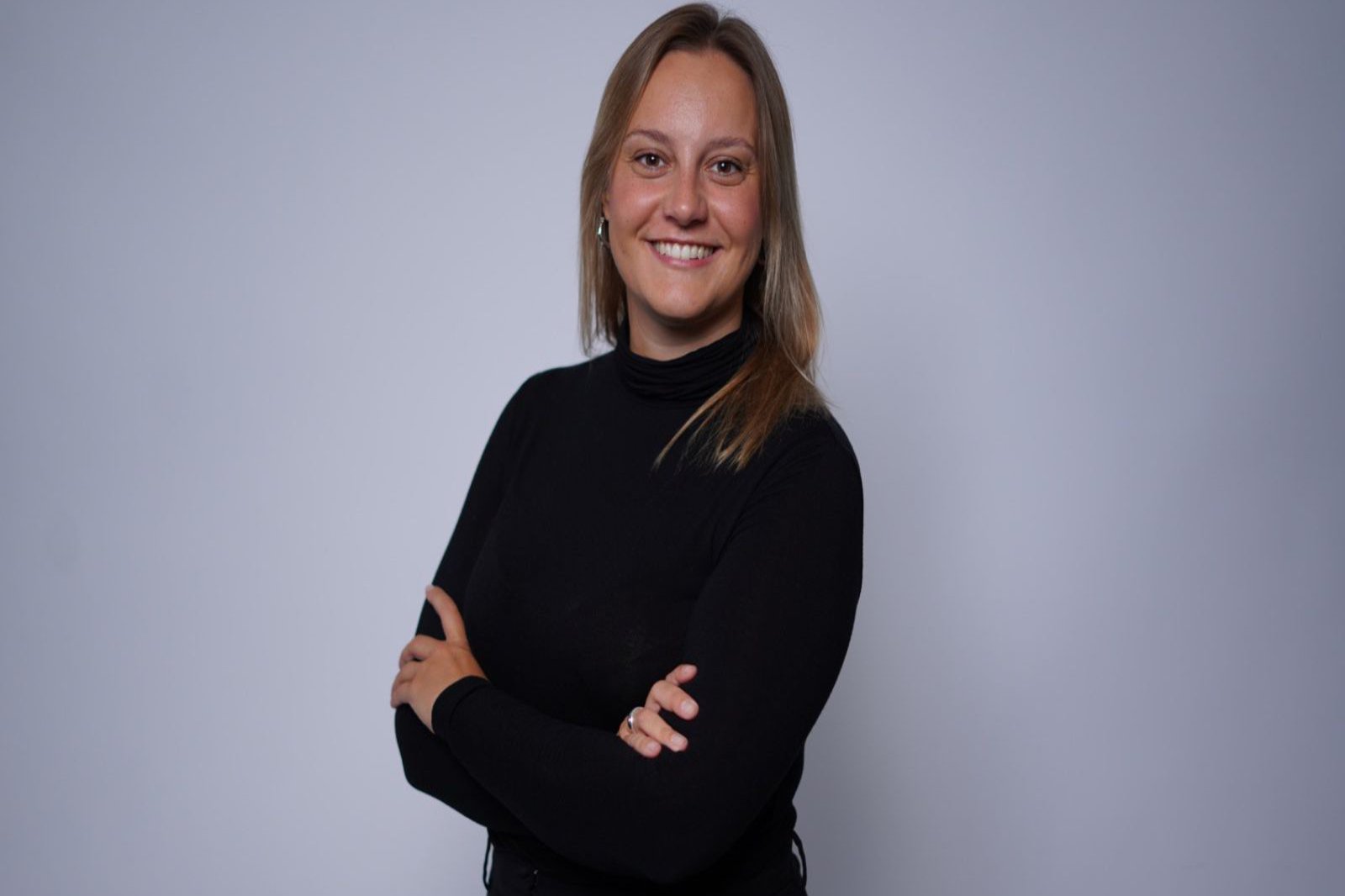 Portrait of a woman standing sideways to the camera with her arms crossed